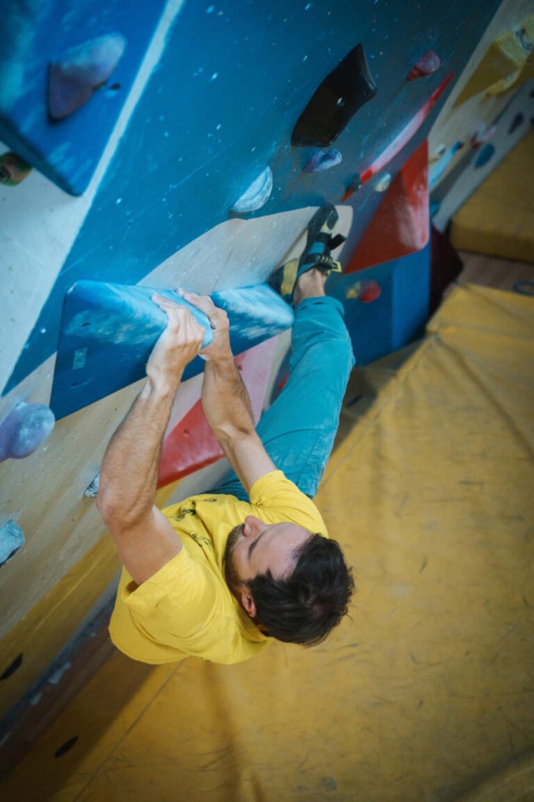 Climber in azione su un blocco boulder strapiombante, presa a due mani